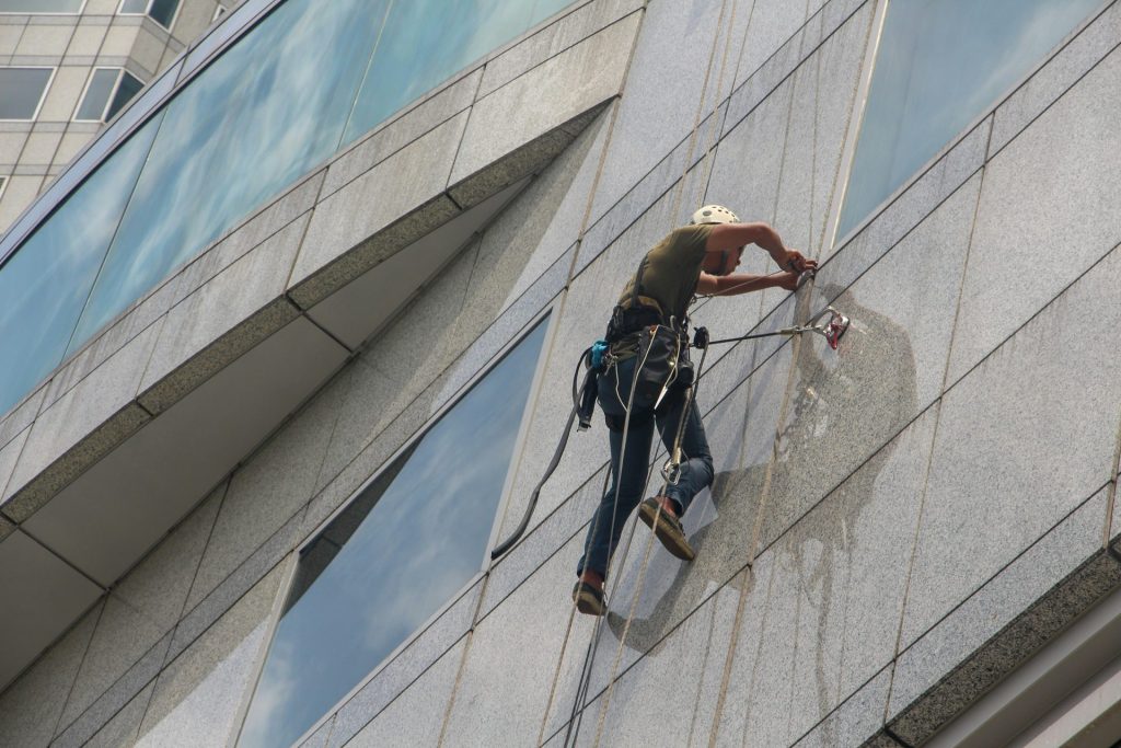 Mann am Seil reinigt Fassade, T&S Hausmeisterservice